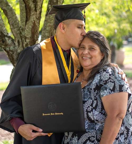 A young man graduating from university giving his Mum a hug